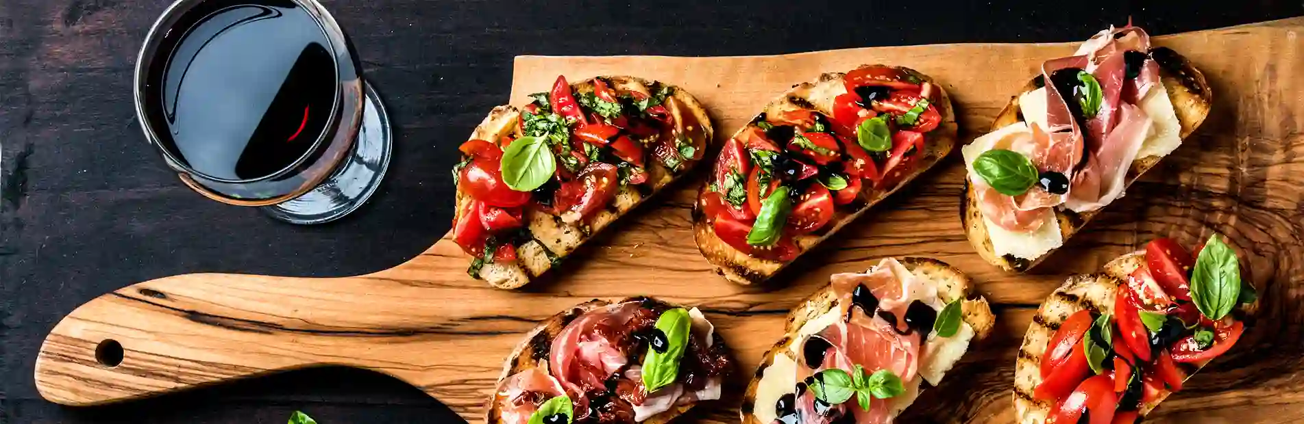 A mouthwatering image of bruschetta topped with ripe tomatoes, fresh basil, and drizzled with olive oil, served on a rustic wooden board